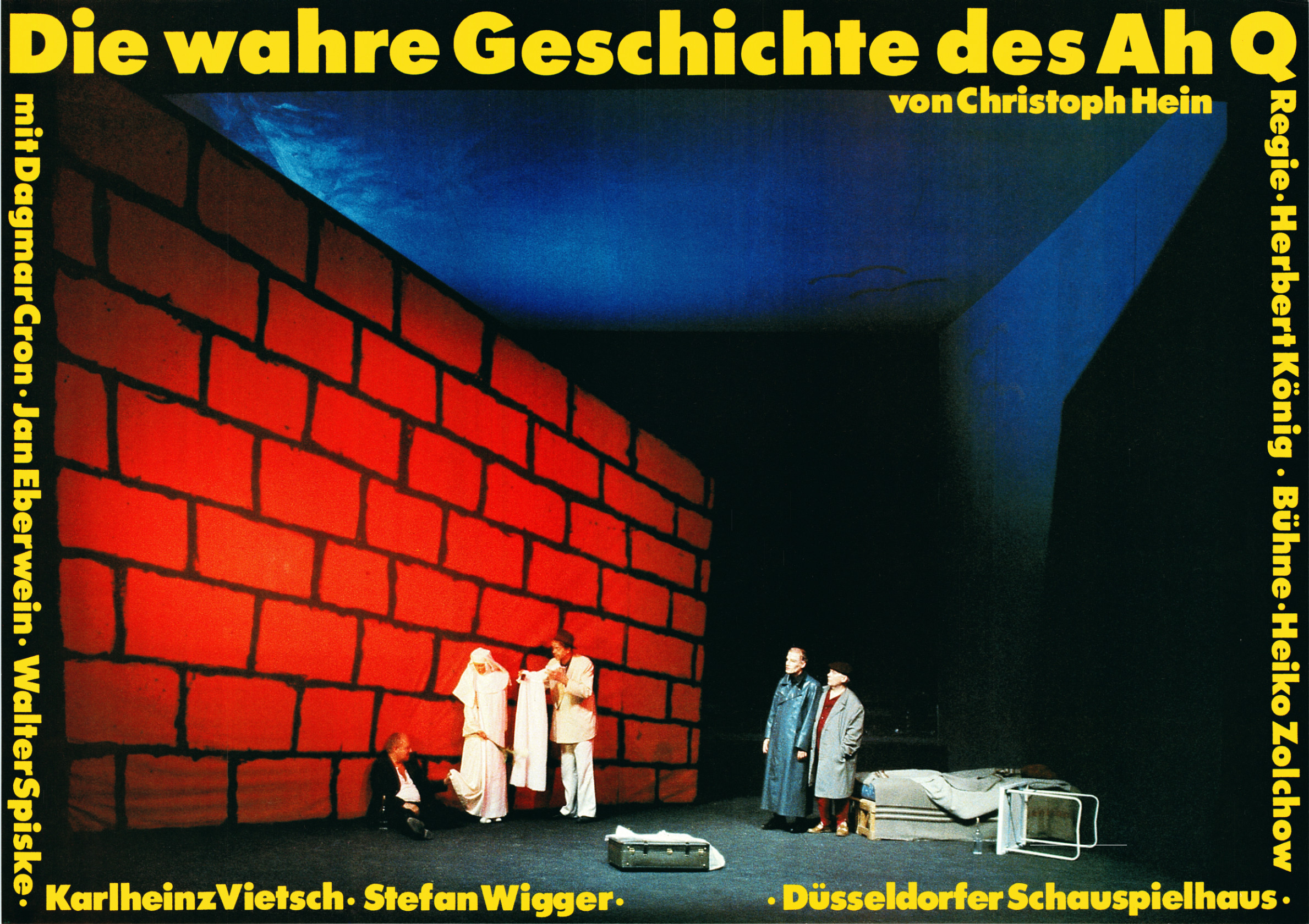 farbiges Plakat mit Szenenfoto, auf dem vier Schauspieler und eine Schauspielerin vor einer von links bis zur B&uuml;hnenmitte hineinragenden roten Ziegelwand sitzen oder stehen, rechterhand liegen Matratzen auf einer Palette, daneben ein umgest&uuml;rzter kleiner Tisch; umrahmt wird das Foto von gelber Schrift, die Titel, Autor, Regieteam, Mitwirkende sowie das Theater nennt